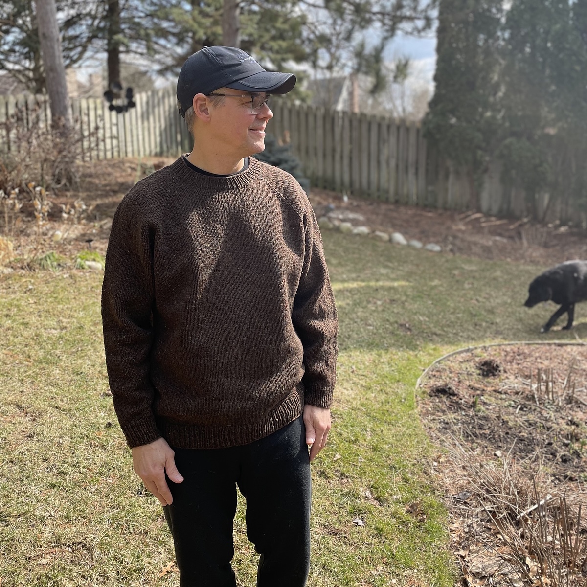 square photo of man in brown sweater and ball cap