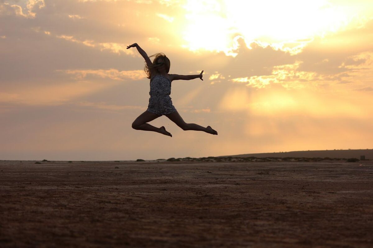 silhouette of woman jumping with sunset in the background 