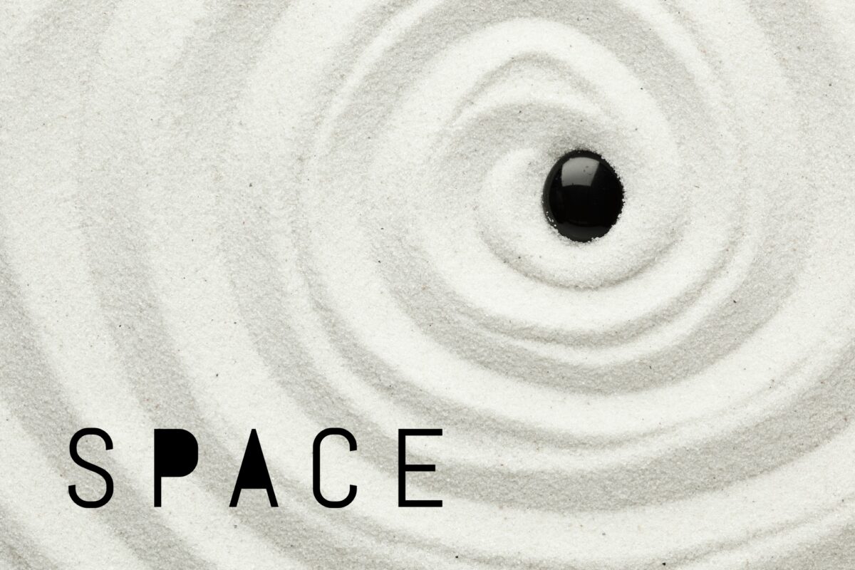 black pepple in white swirled sand with word space